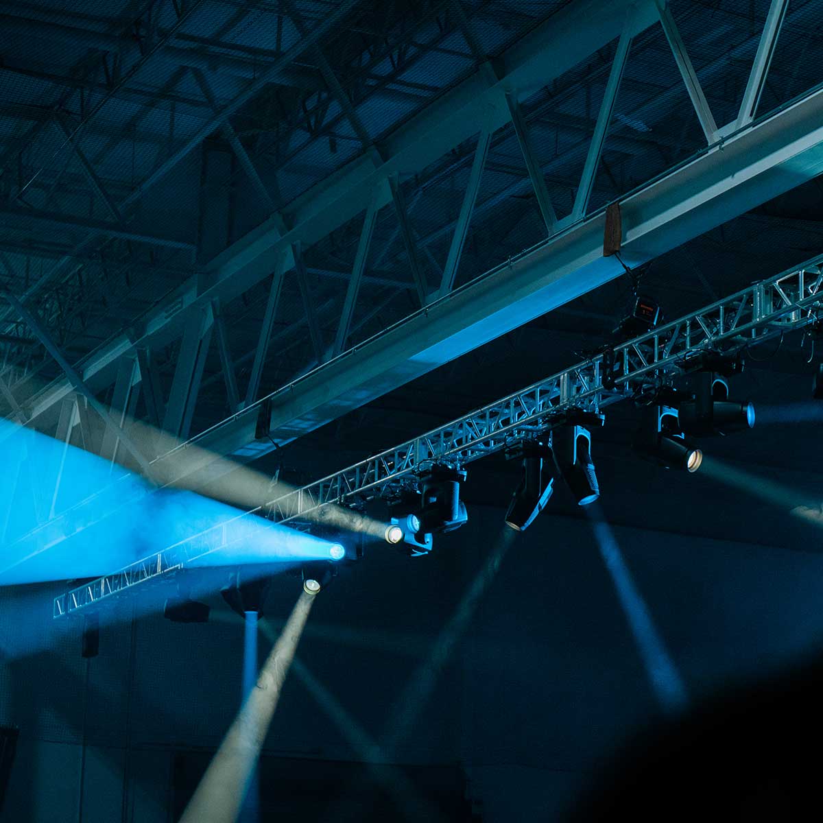 Overhead view of stage lighting equipment and beams in a large indoor venue