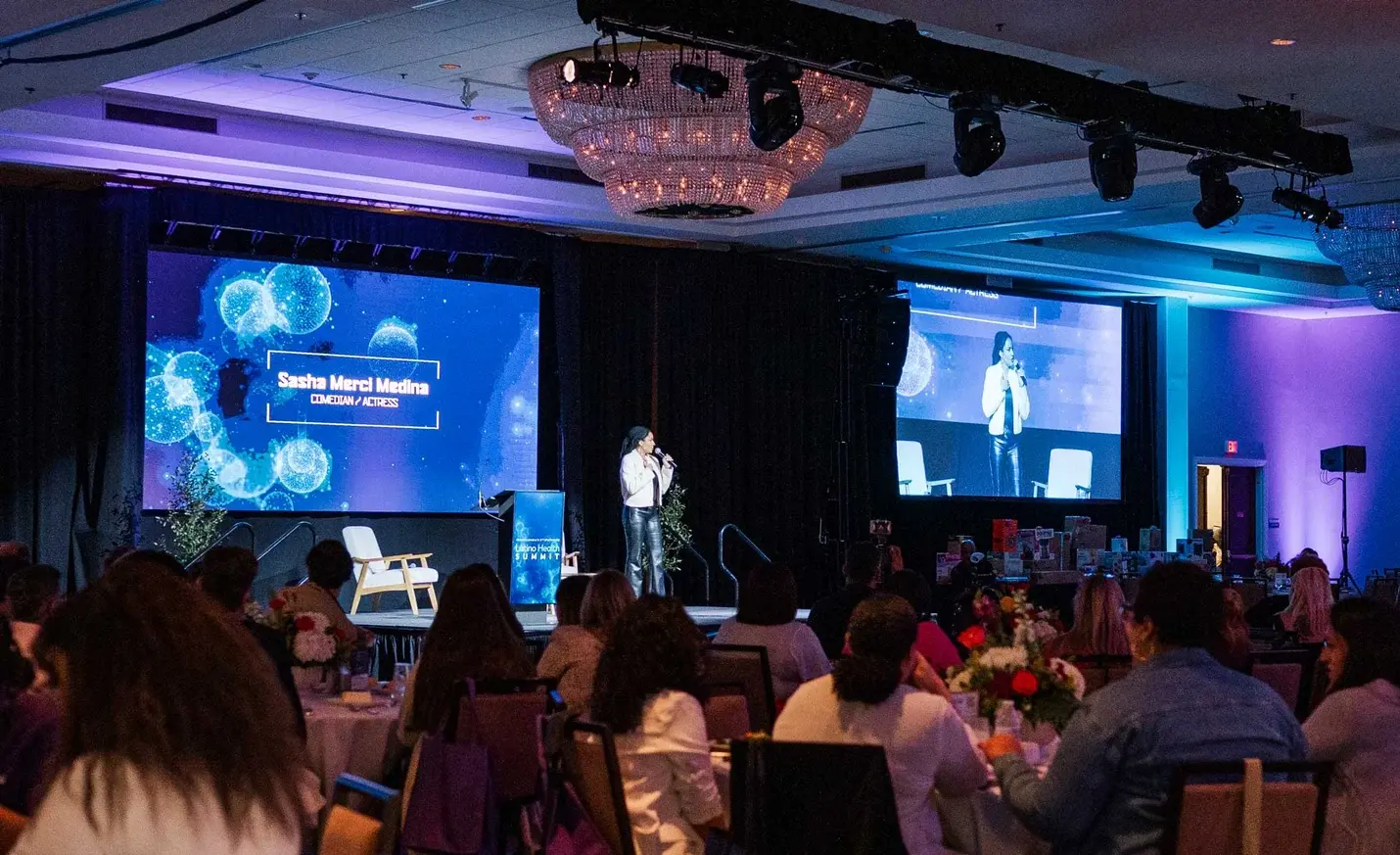 A speaker on stage before a seated audience at the Latino Health Summit